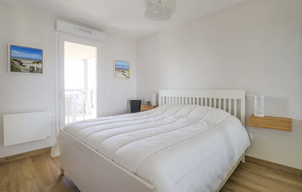 A bright bedroom with a large bed and a glass door opening onto a balcony.