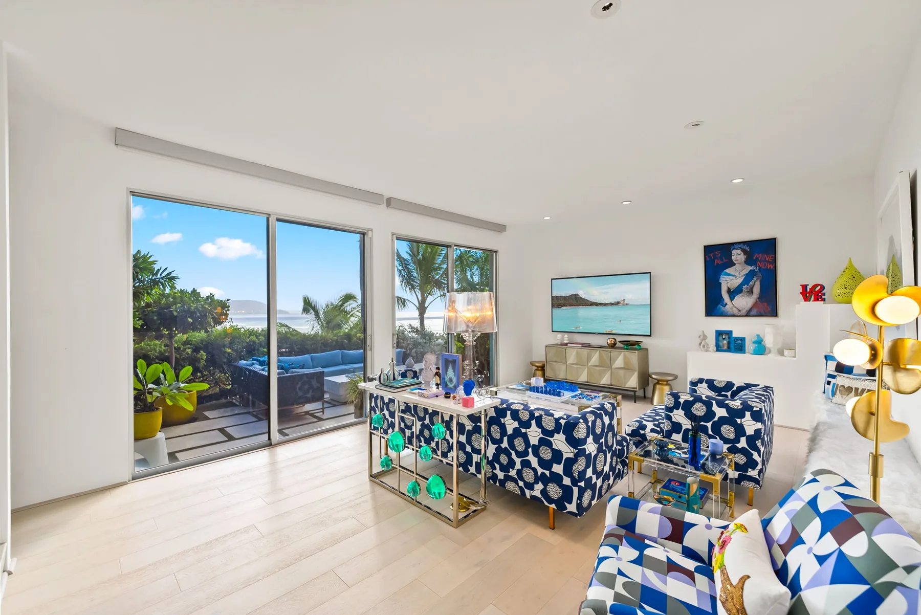 A bright living room opens onto a patio through large glass doors.