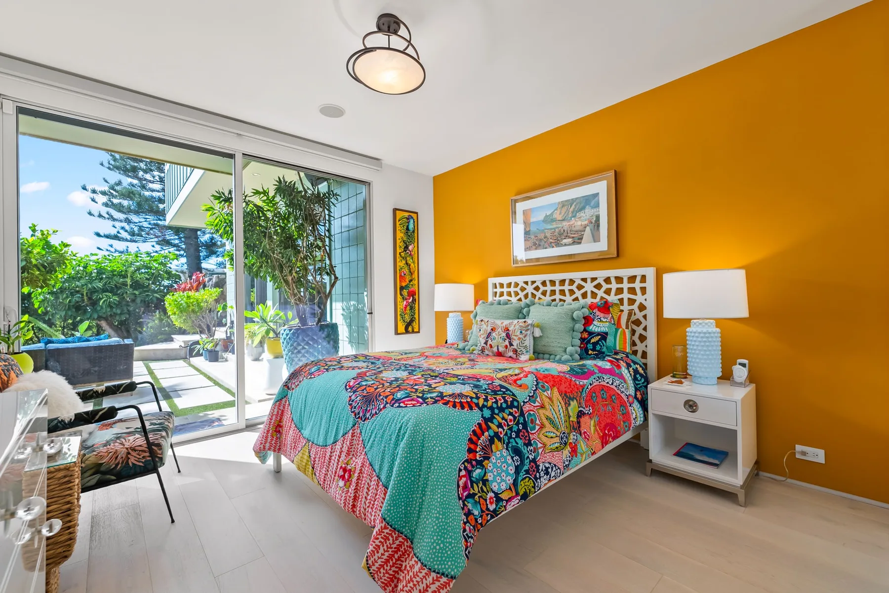 A colorful bedroom with a patterned bed beside large sliding glass doors.