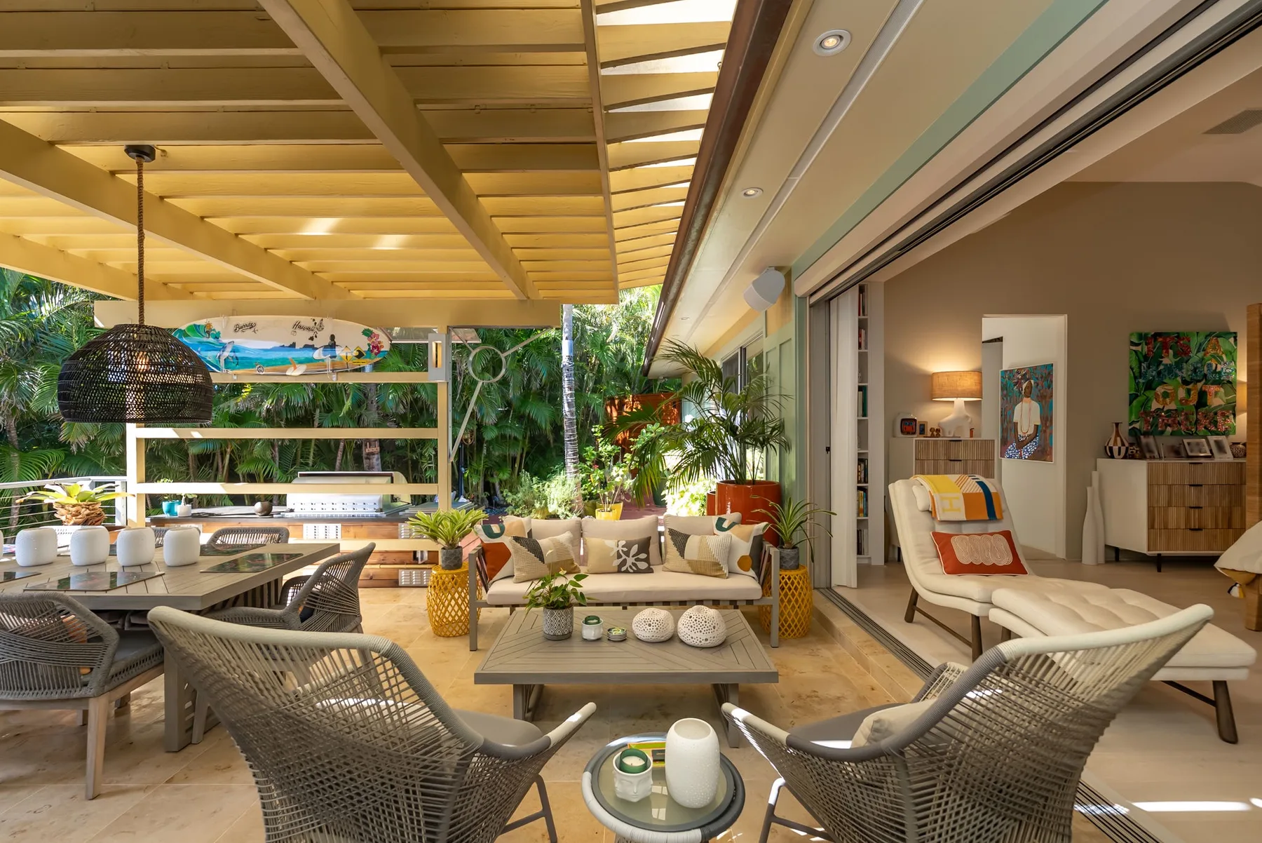 A bright open-plan living area with seating, a low table, and a covered patio.