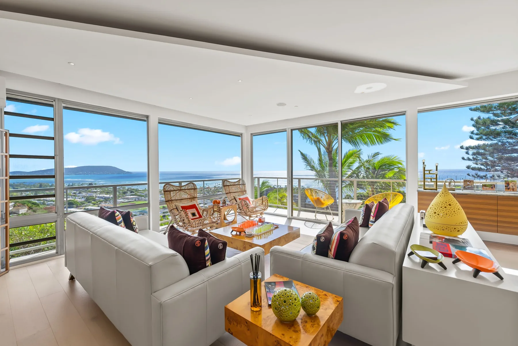 A bright living room opens onto a balcony with a view of the water.