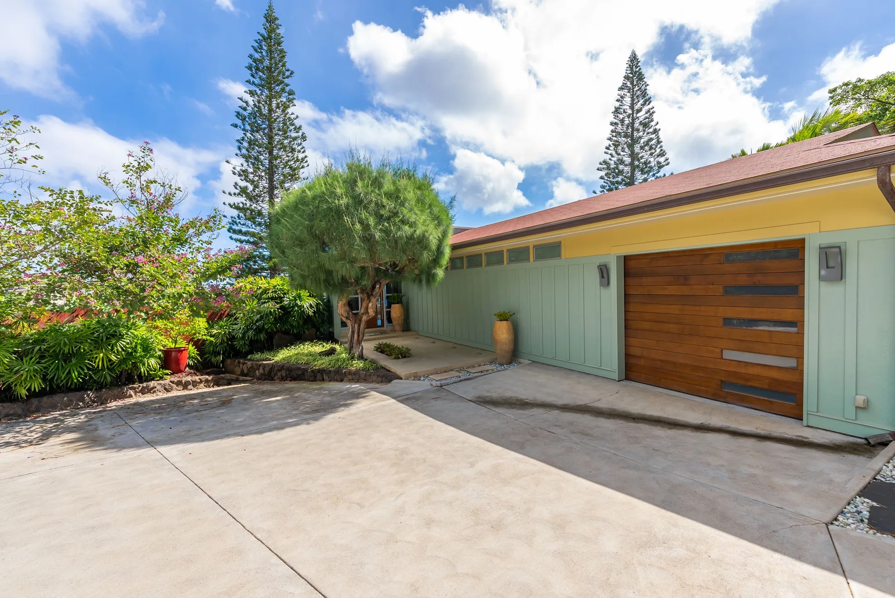 A house exterior with a wide driveway, garage door, and landscaped garden.