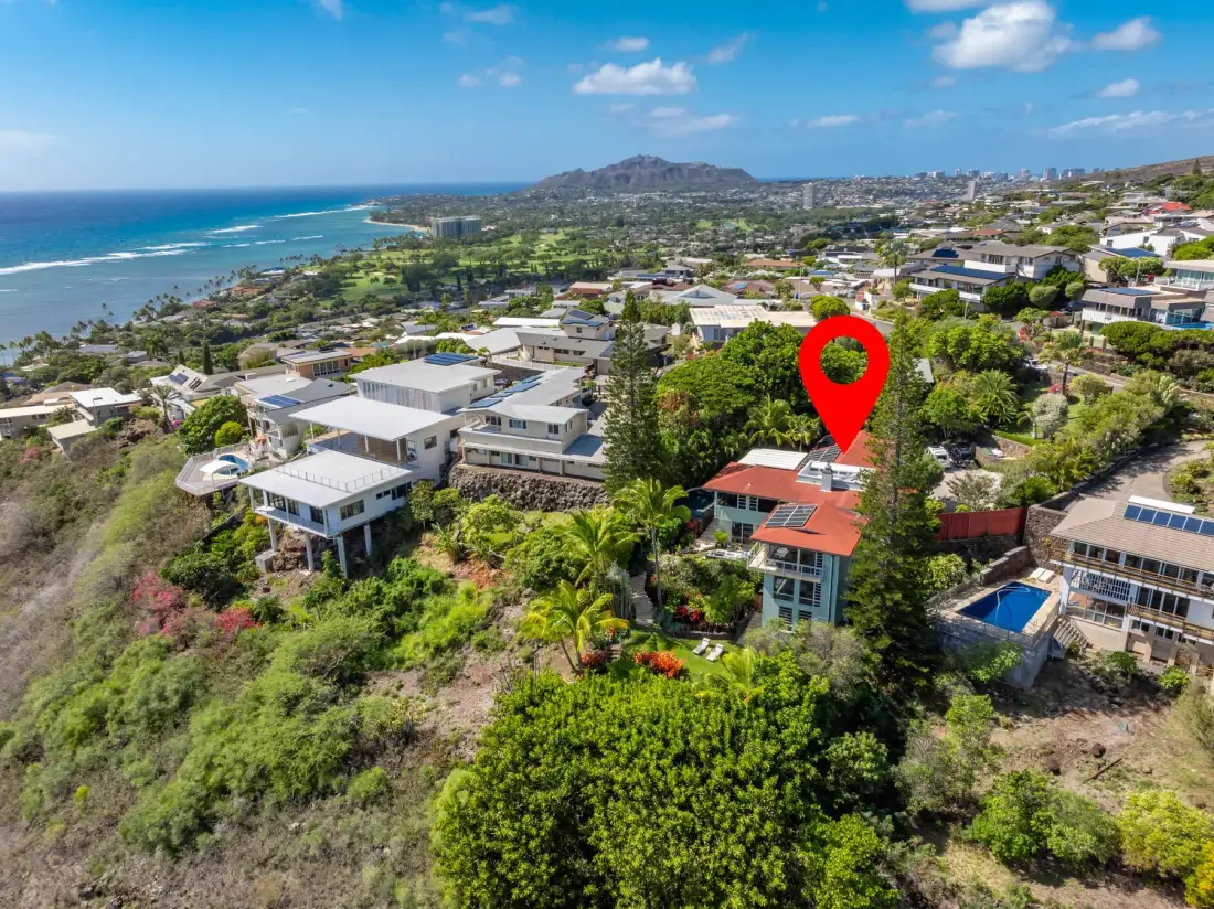 Aerial view of a coastal neighborhood with homes, greenery, and the ocean.