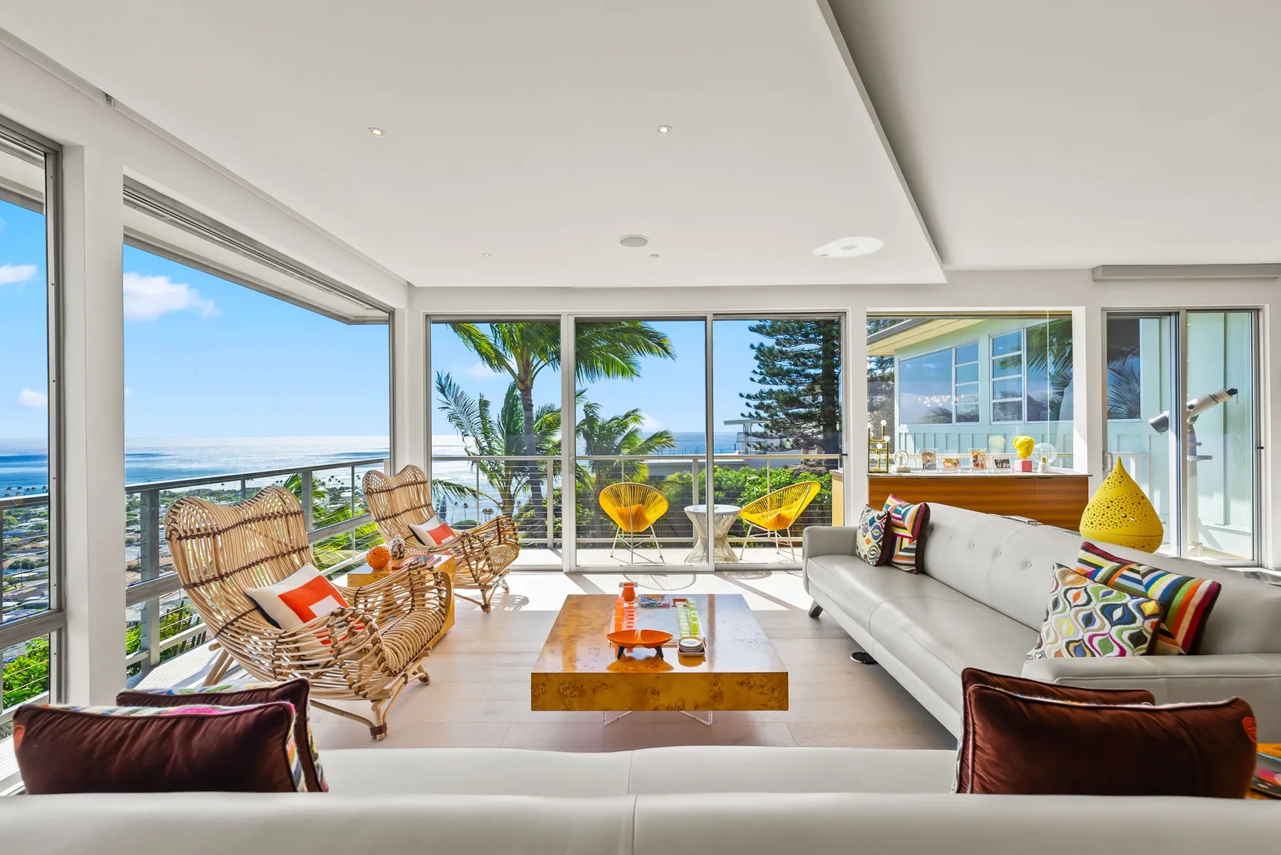 A bright living room with seating, a coffee table, and large windows overlooking the ocean.
