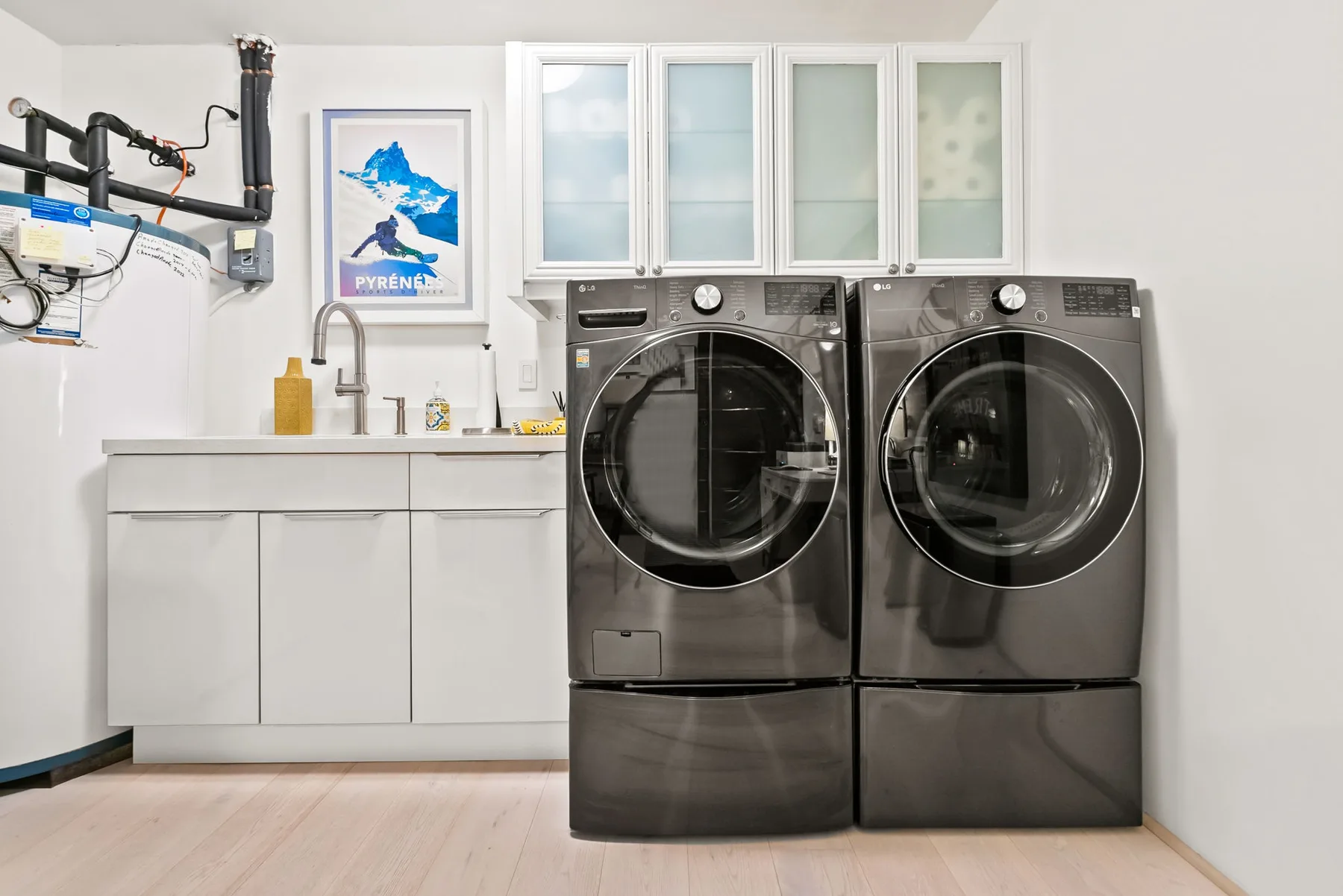 A laundry room with two front-loading machines beside a utility sink.