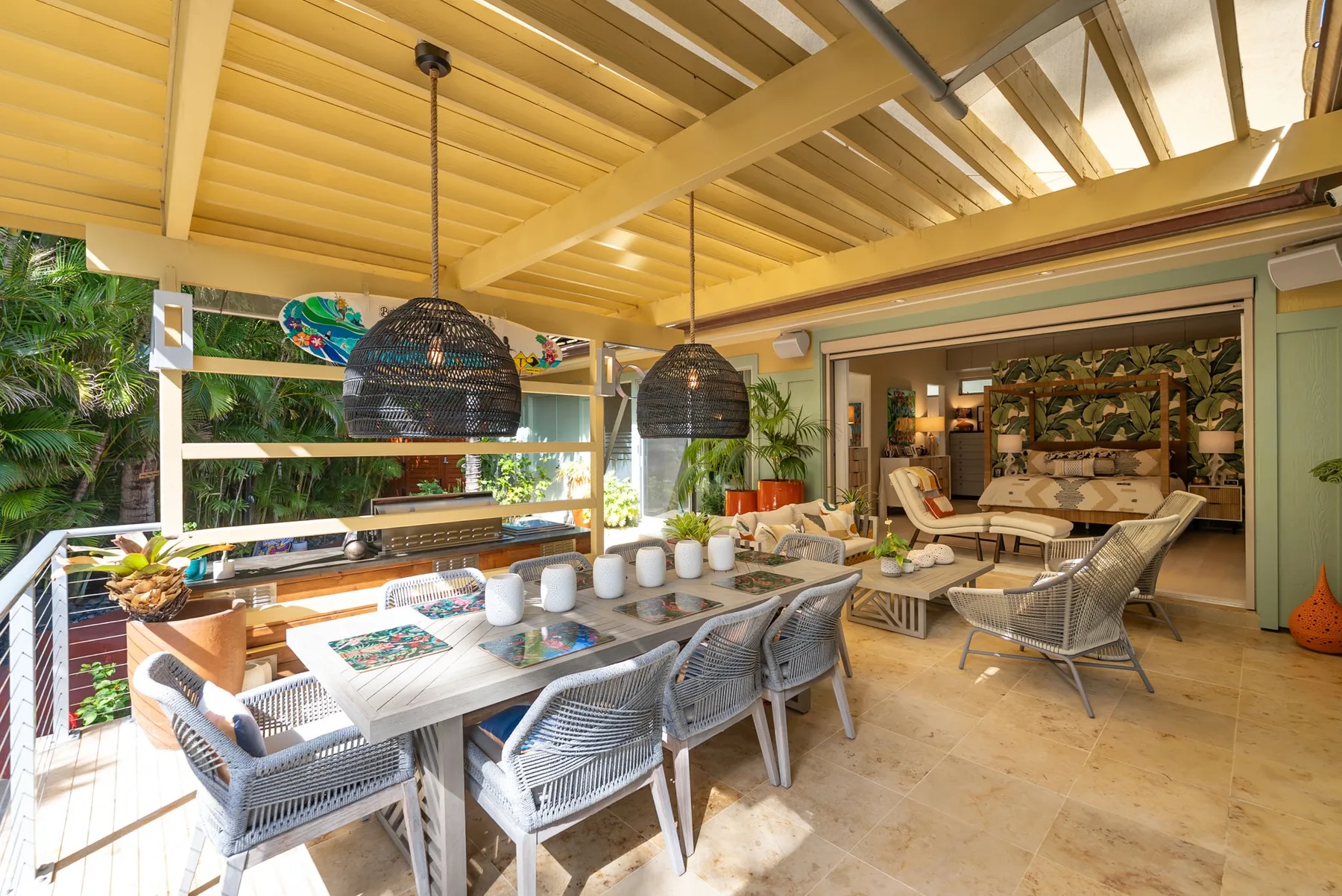 A covered outdoor dining and lounge area with a long table and woven seating.
