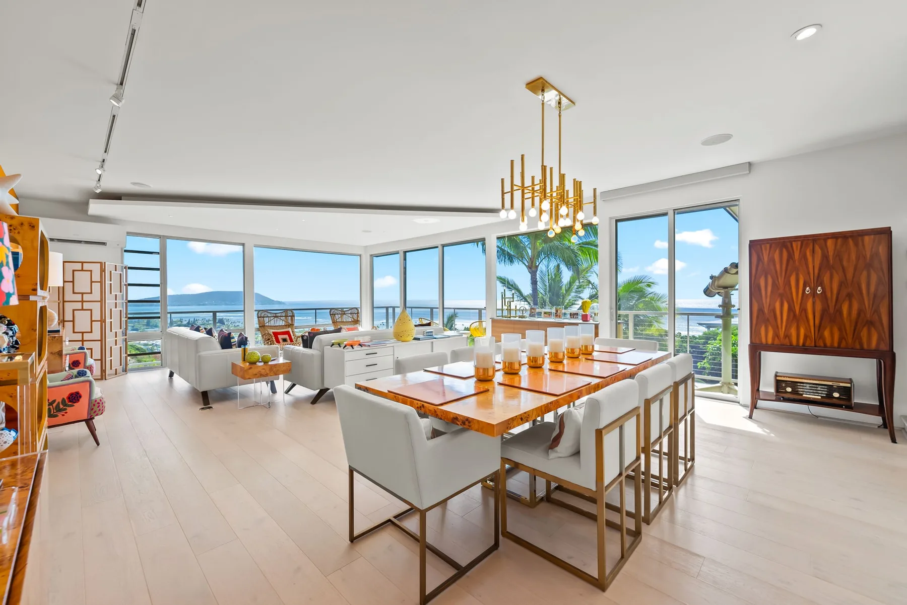 A bright open-plan living and dining area with large windows overlooking the ocean.
