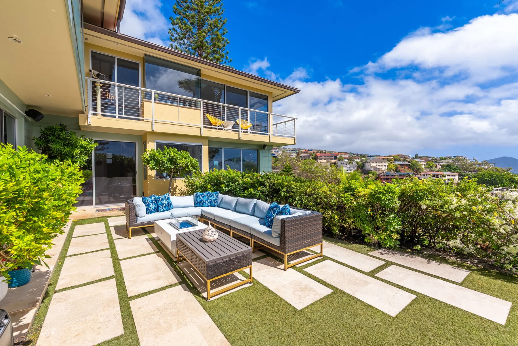 A patio with outdoor seating overlooks a landscaped hillside.