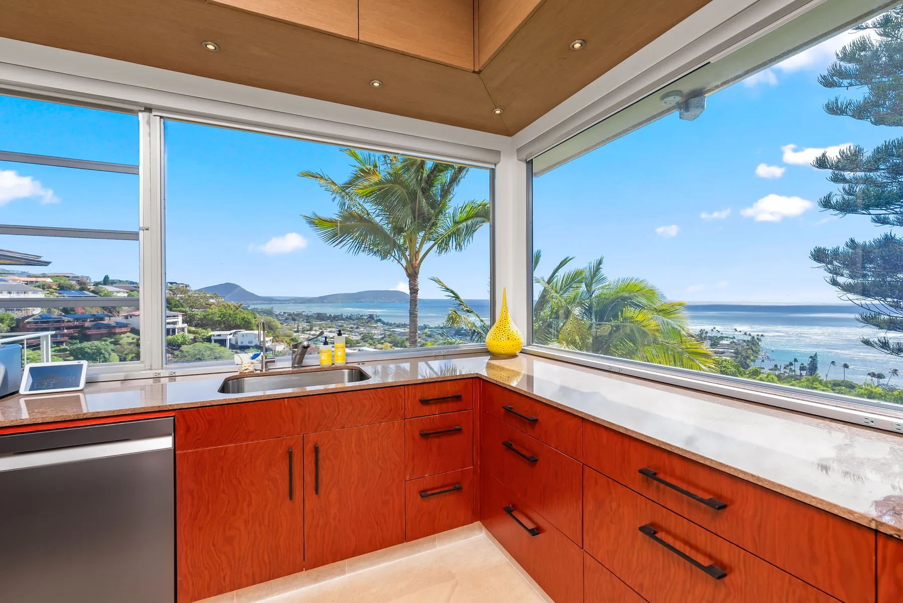A kitchen with wooden cabinetry and wide windows overlooking the ocean.