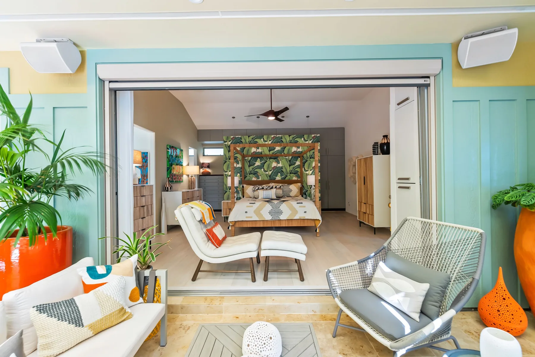 A colorful bedroom opens onto a sitting area with a canopy bed and lounge seating.