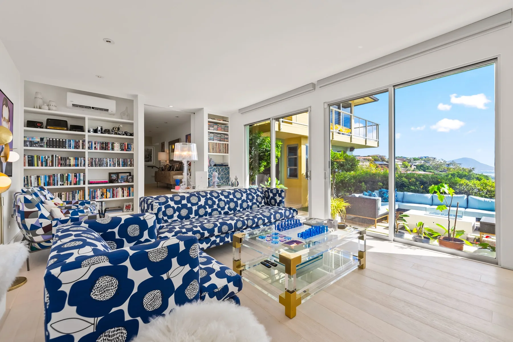 A bright living room with patterned seating and large windows opening onto a terrace.
