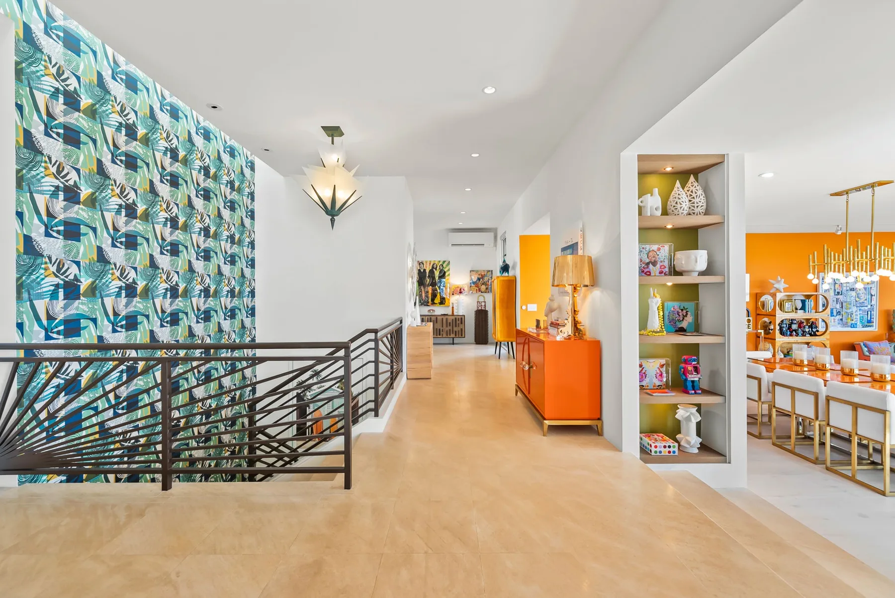 A bright open interior with a stair railing, colorful wall, and dining area.