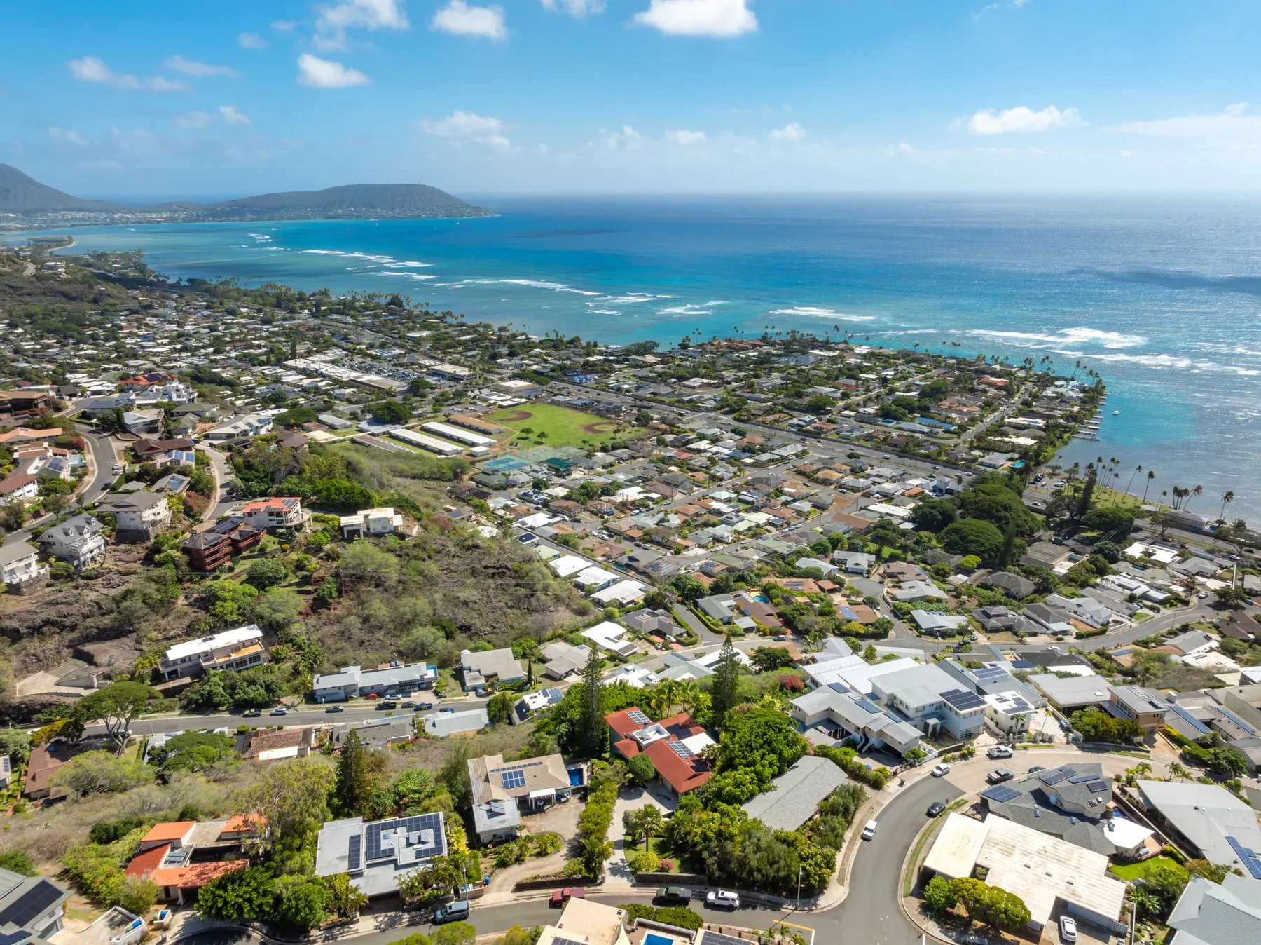 Aerial view of a coastal neighborhood beside a turquoise bay.
