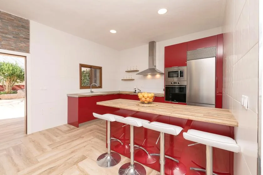 A modern kitchen with red cabinetry and a long island with bar seating.