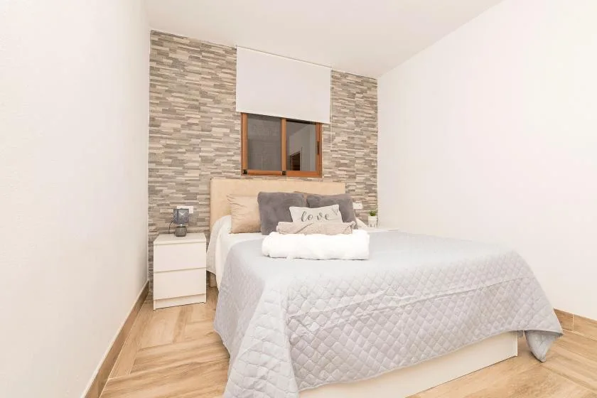 A bedroom with a neatly made bed beneath a window.