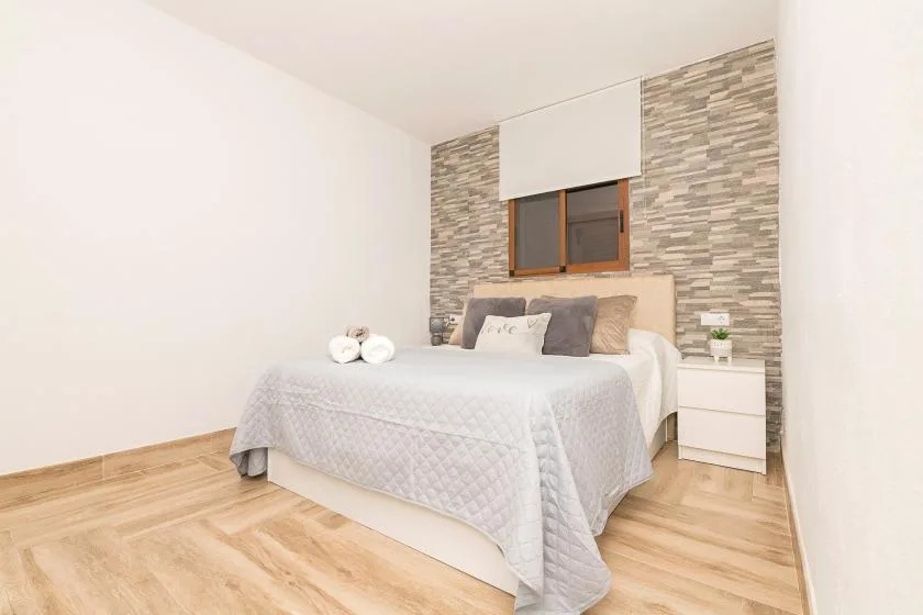 A bedroom with a neatly made bed beneath a window.