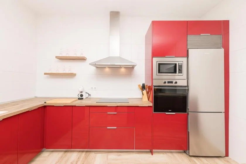 A bright kitchen with red cabinetry, a stainless-steel refrigerator, and built-in appliances.