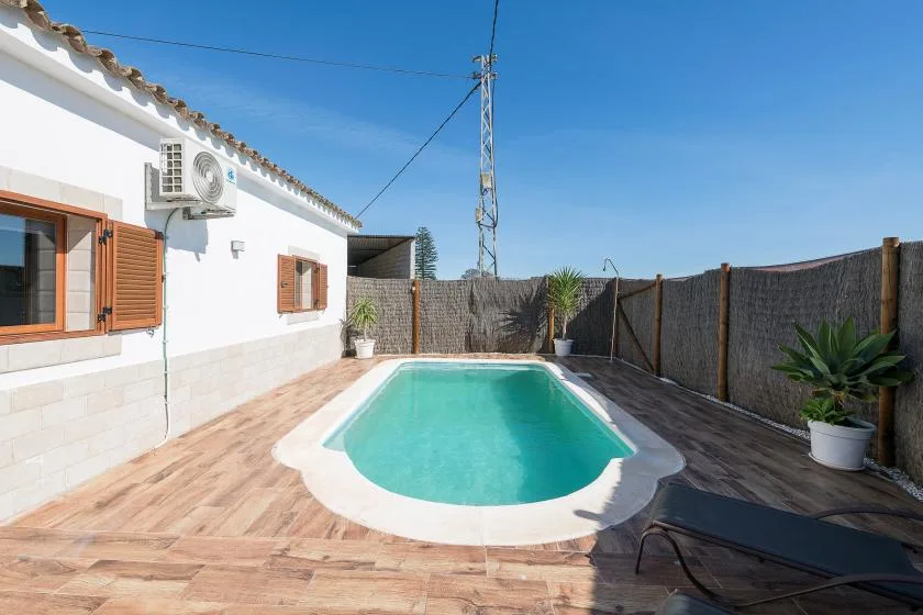 An outdoor swimming pool beside a white building, with a paved deck.