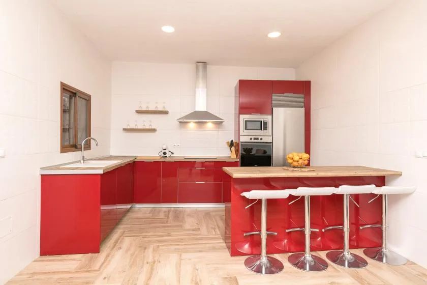 A bright kitchen with red cabinets and a central island with seating.