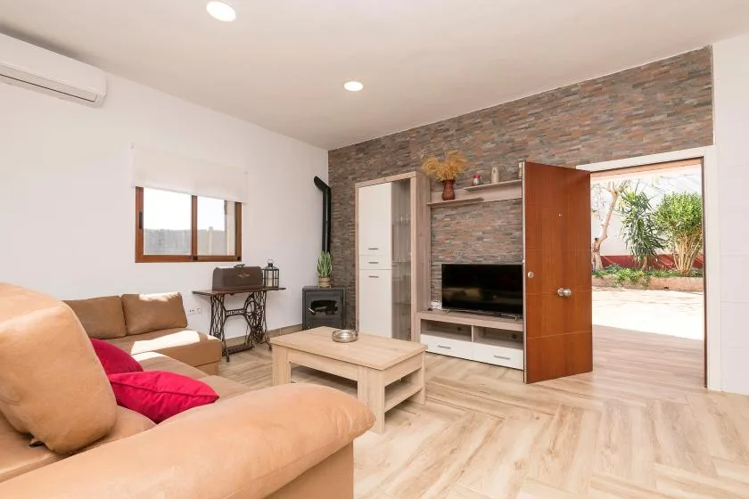 A living room with seating, a television, and an open door to a patio.