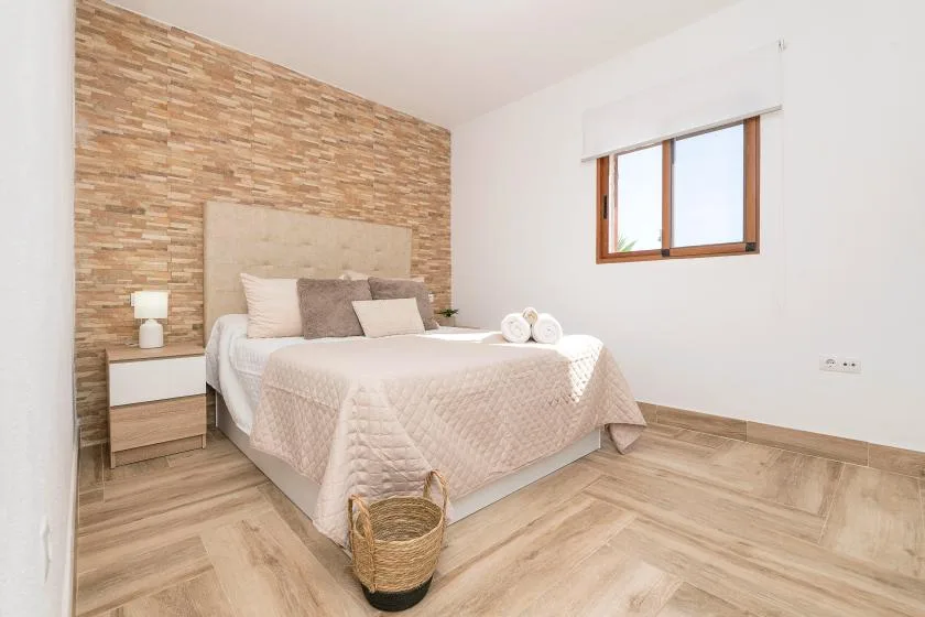 A bedroom with a made bed, bedside table, and window.