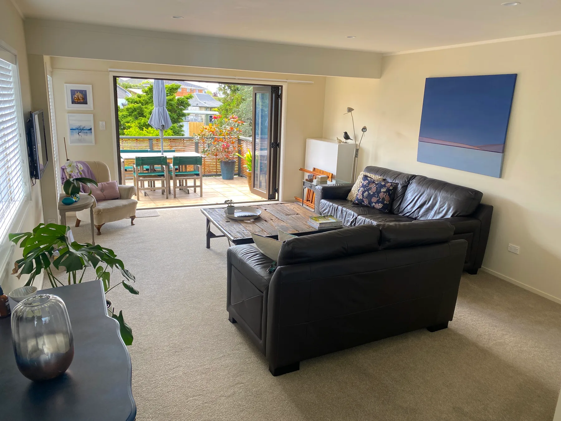 A living room with seating and a coffee table beside an open patio.