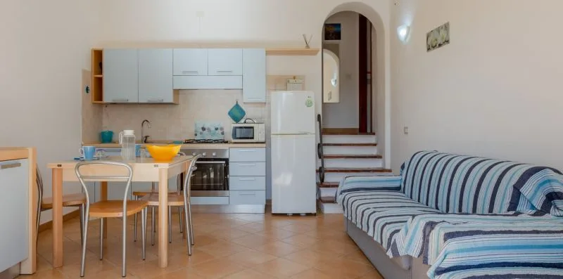 Una cocina y comedor con un sofá a rayas junto a la mesa.