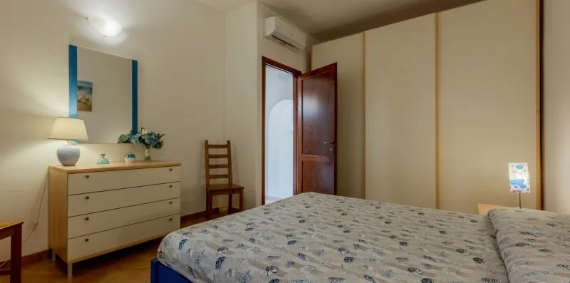 Un dormitorio con una cama estampada, una cómoda y una puerta abierta.