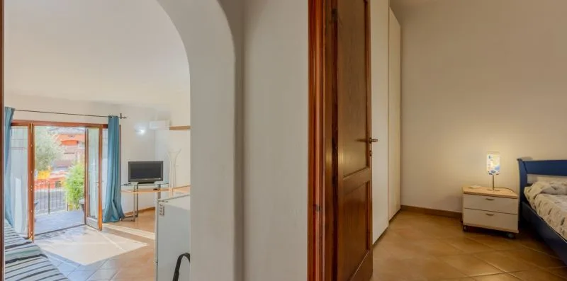 Un dormitorio con una cama y una mesita de noche, visto desde una puerta abierta.
