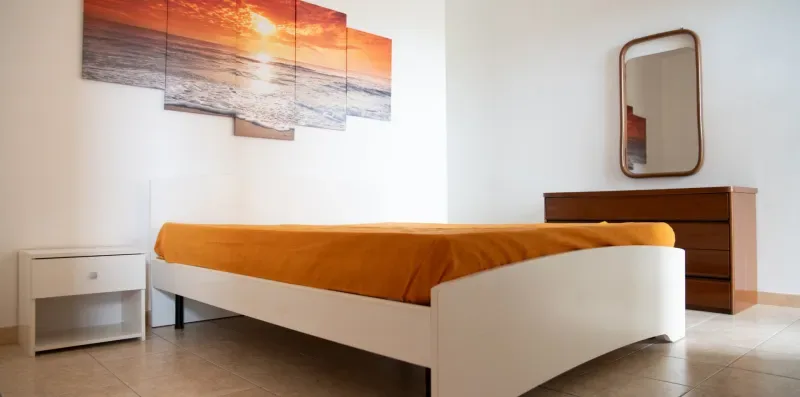 Un dormitorio con una cama cubierta de naranja y una cómoda de madera.