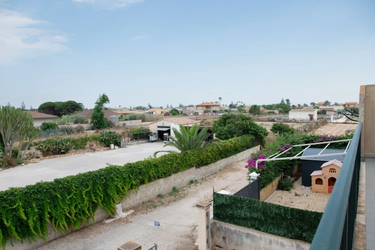 Vista de un barrio residencial, con jardines y tejados bajo un cielo despejado.