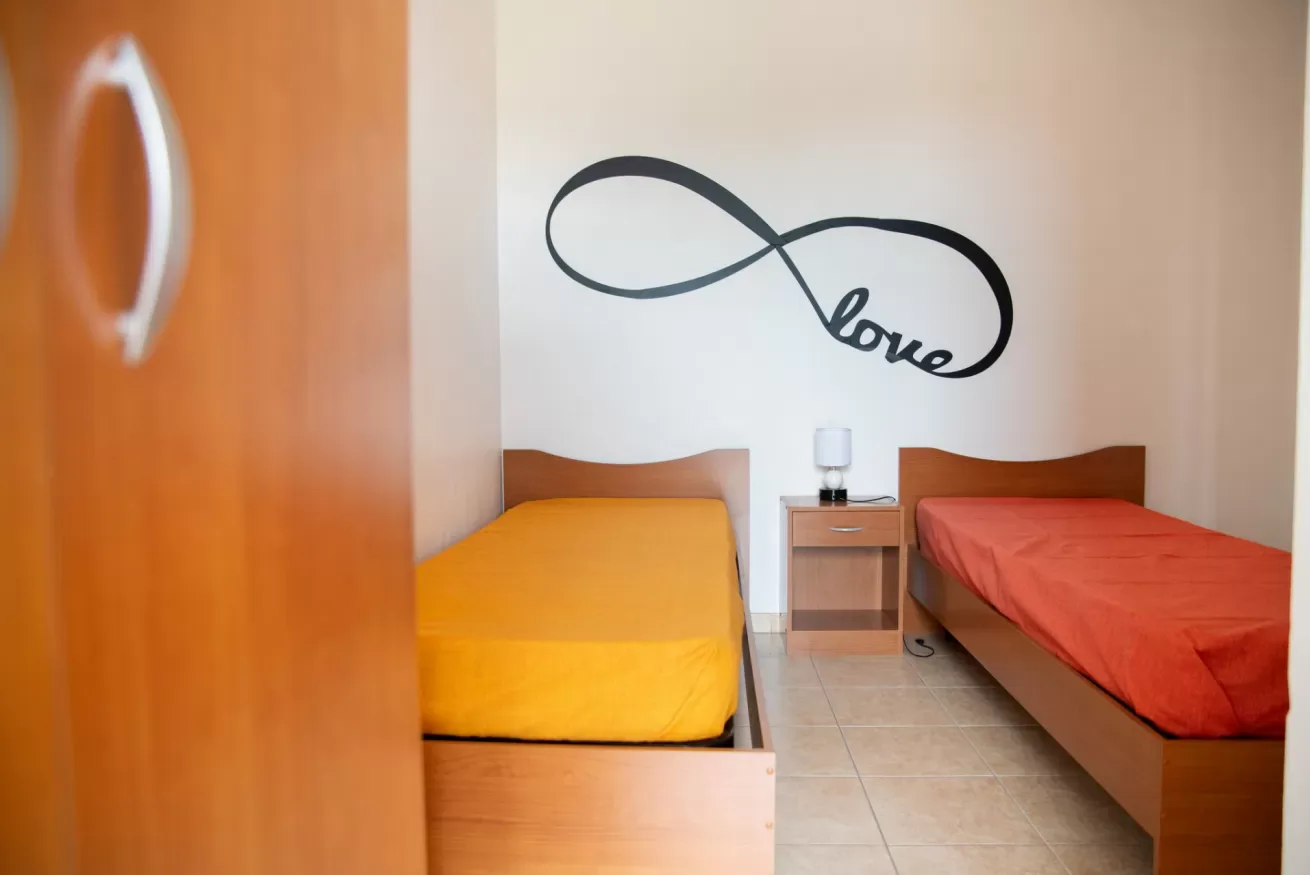 Un dormitorio con dos camas individuales y un adorno de pared en forma de infinito.
