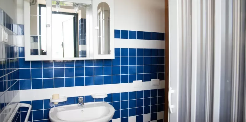 Un baño alicatado con un lavabo blanco y un armario con espejo.