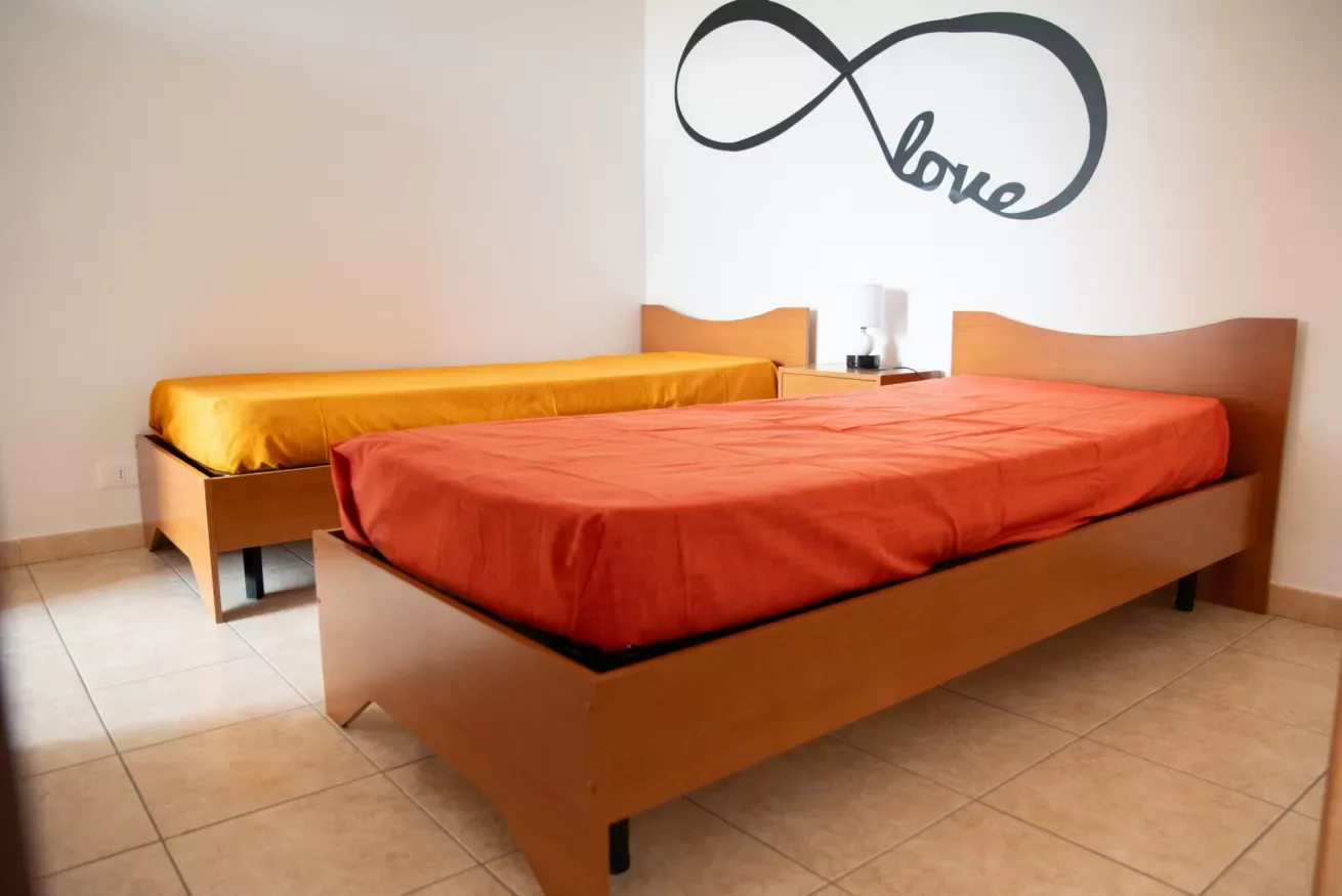 Un dormitorio con dos camas, una cubierta con ropa de cama roja y la otra amarilla.