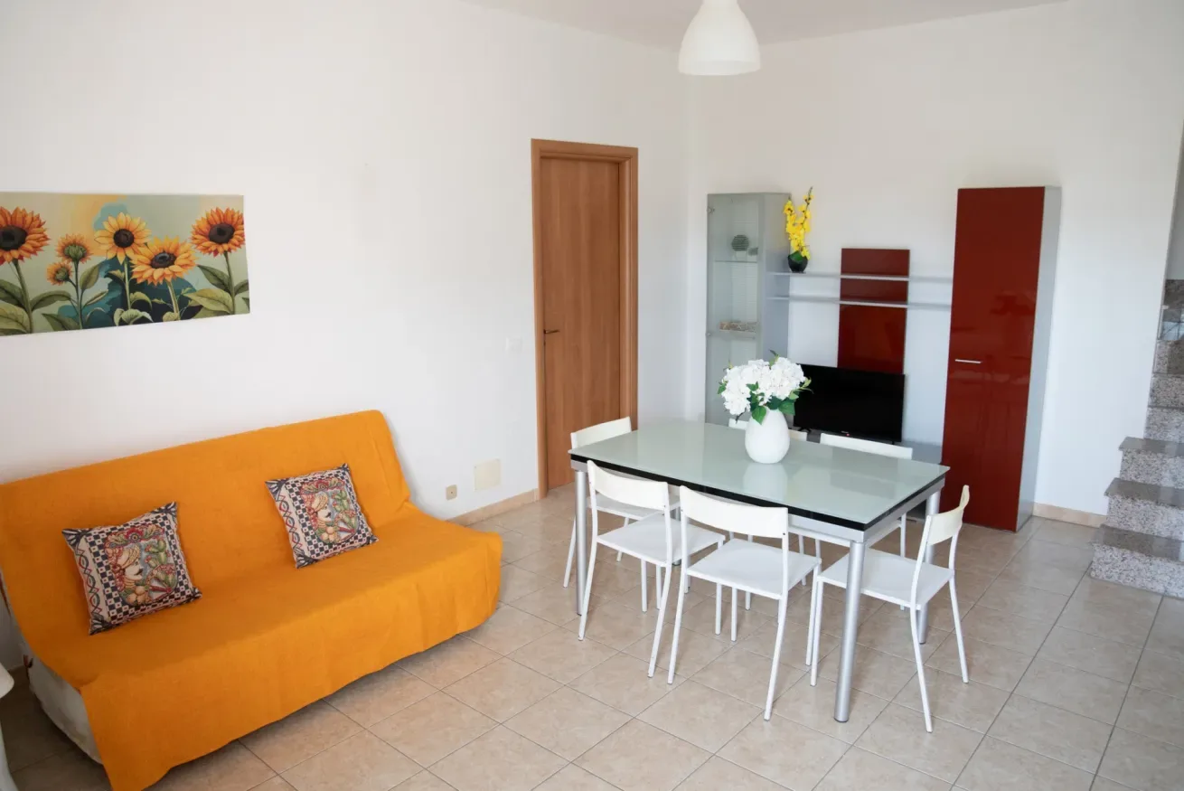 Una luminosa sala de estar y comedor con asientos naranjas y una mesa.
