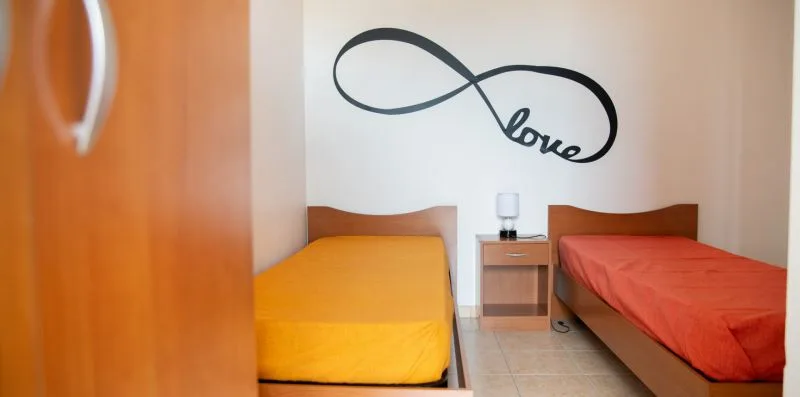 Un dormitorio con dos camas individuales y un adorno de pared en forma de infinito.