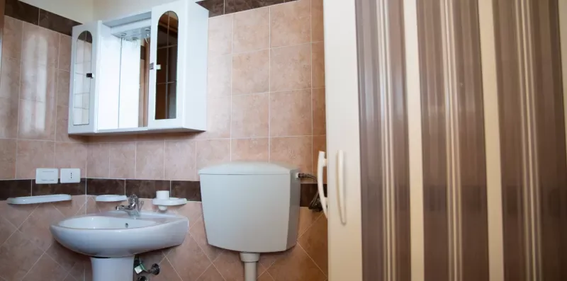 Un baño con azulejos, lavabo, inodoro y un armario con espejo.