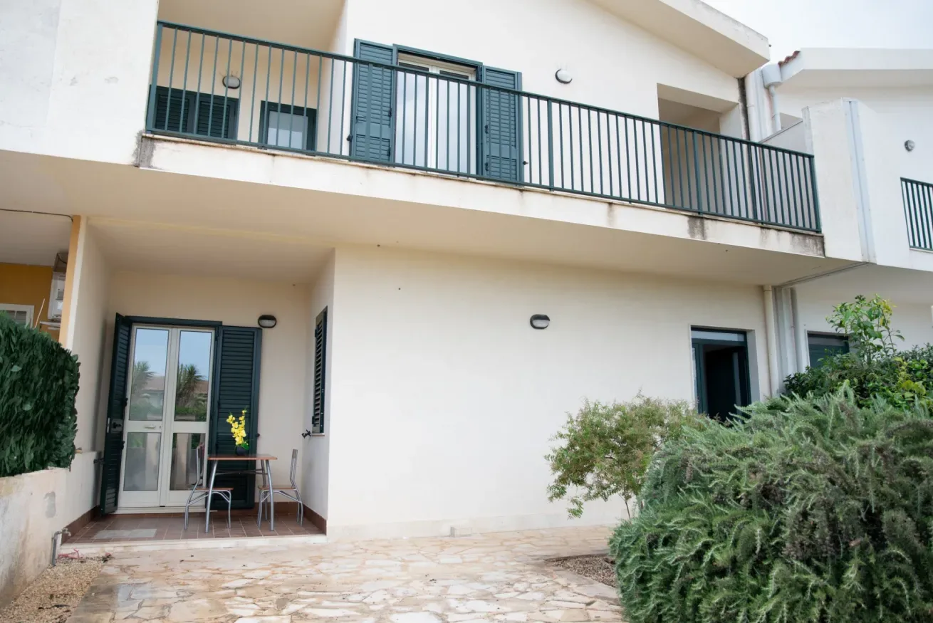 Un edificio blanco de varios niveles tiene un balcón sobre un patio en la planta baja.