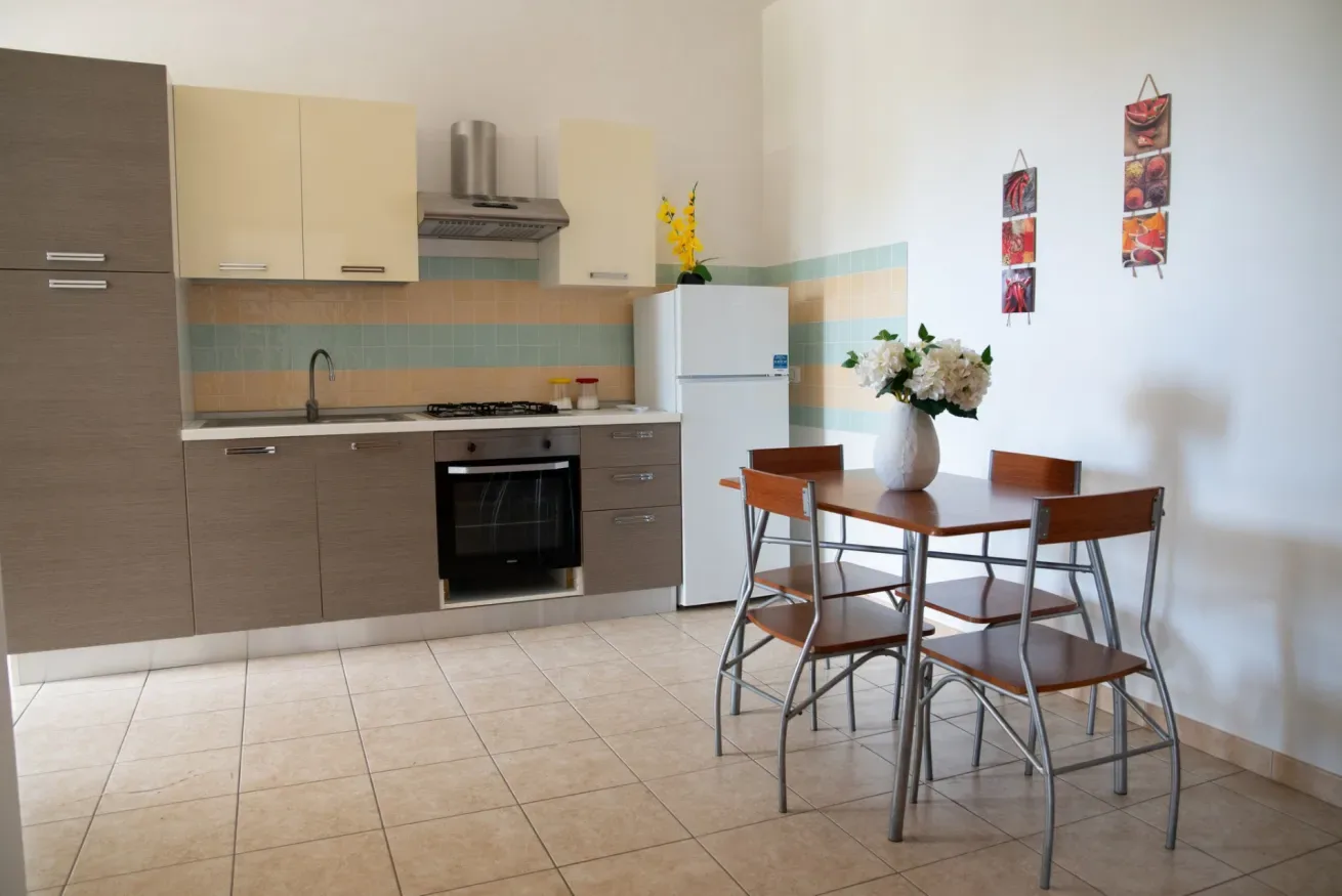 Una cocina y comedor con una mesa, sillas y un refrigerador.