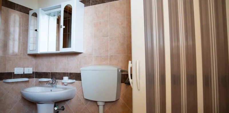 Un baño alicatado con lavabo, inodoro y armario con espejo.