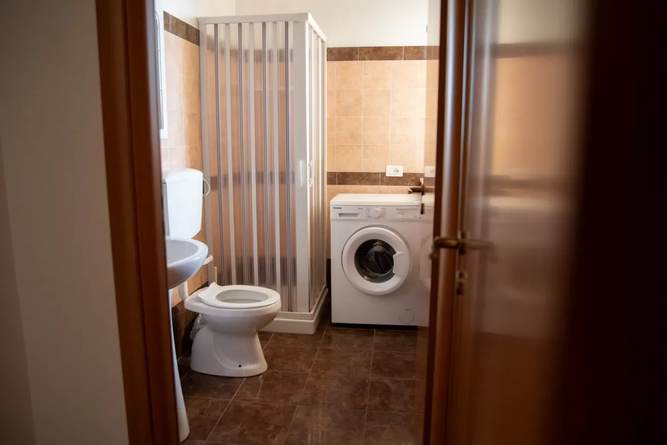 Un baño con ducha, inodoro y lavadora.