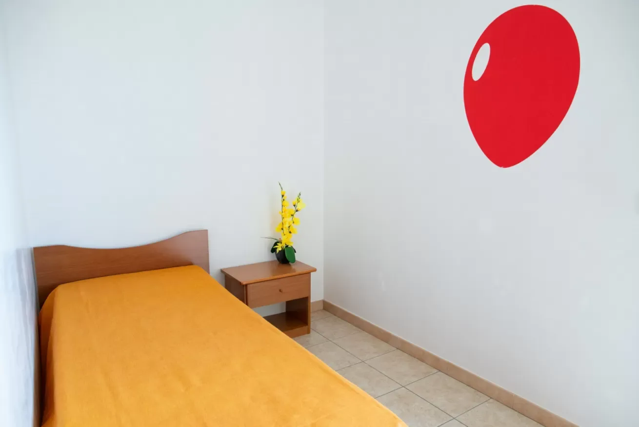 Un dormitorio con una cama cubierta de ropa de cama naranja y una mesita de noche.