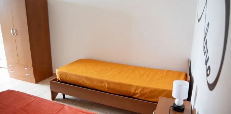 Un dormitorio con una cama cubierta con ropa de cama naranja.