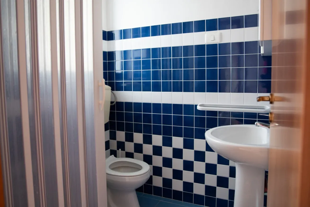 Un baño con azulejos, inodoro y lavabo con pedestal.