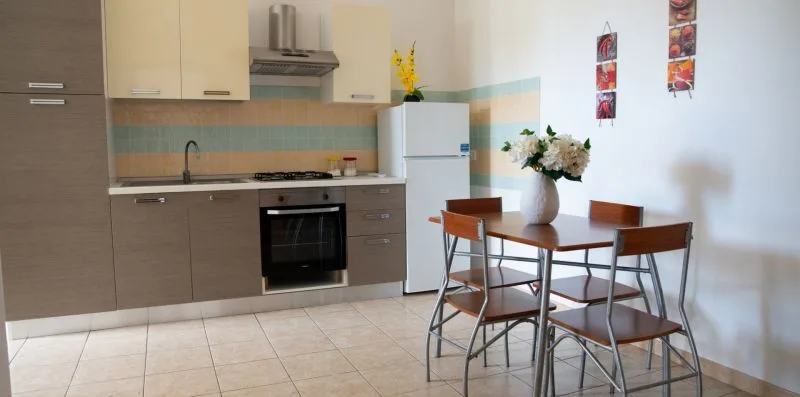 Una cocina y comedor con una mesa y sillas junto a los gabinetes.