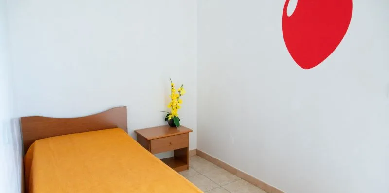 Un dormitorio con una cama cubierta con ropa de cama amarilla y una mesa pequeña.