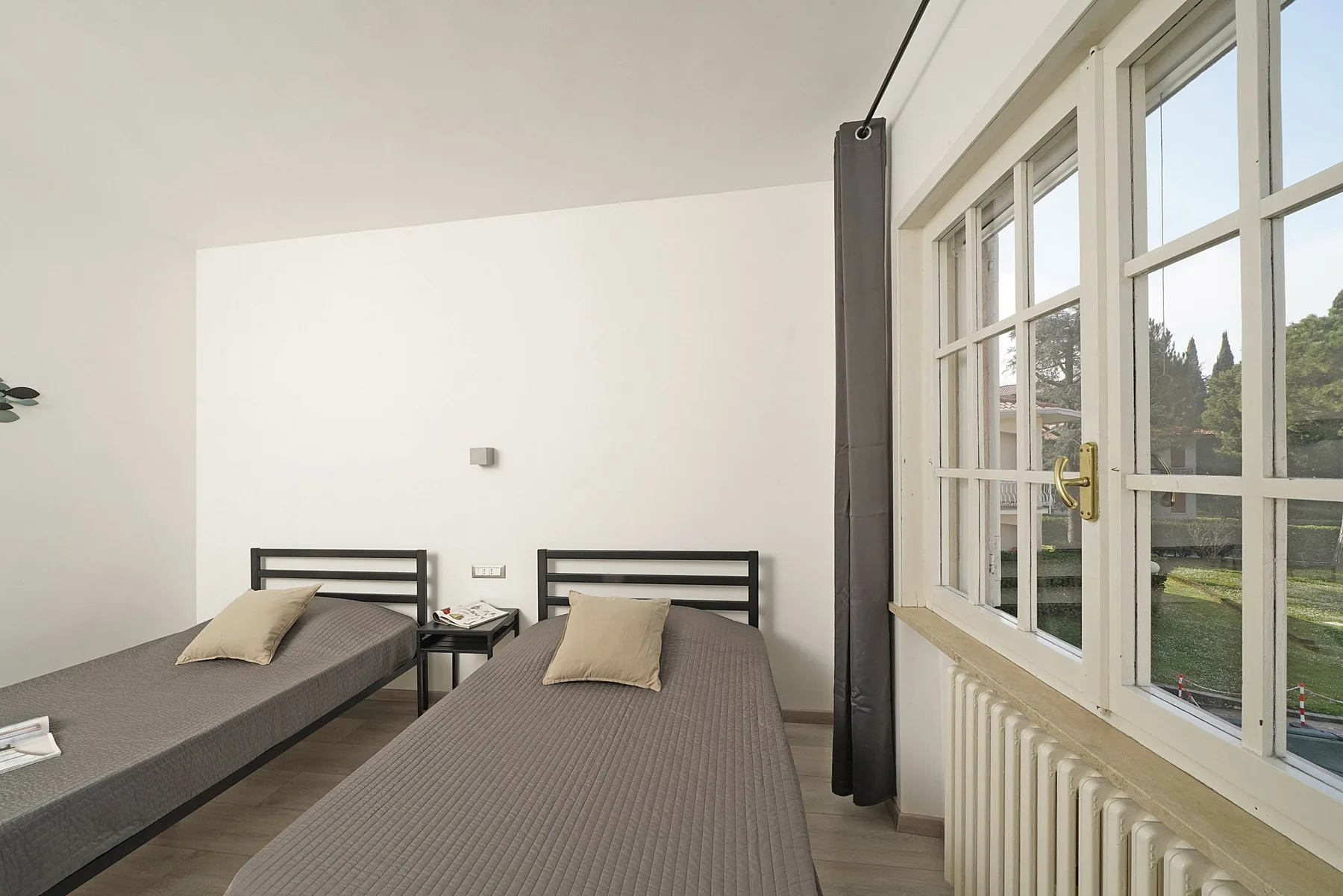 A bright bedroom with two single beds beside large windows.