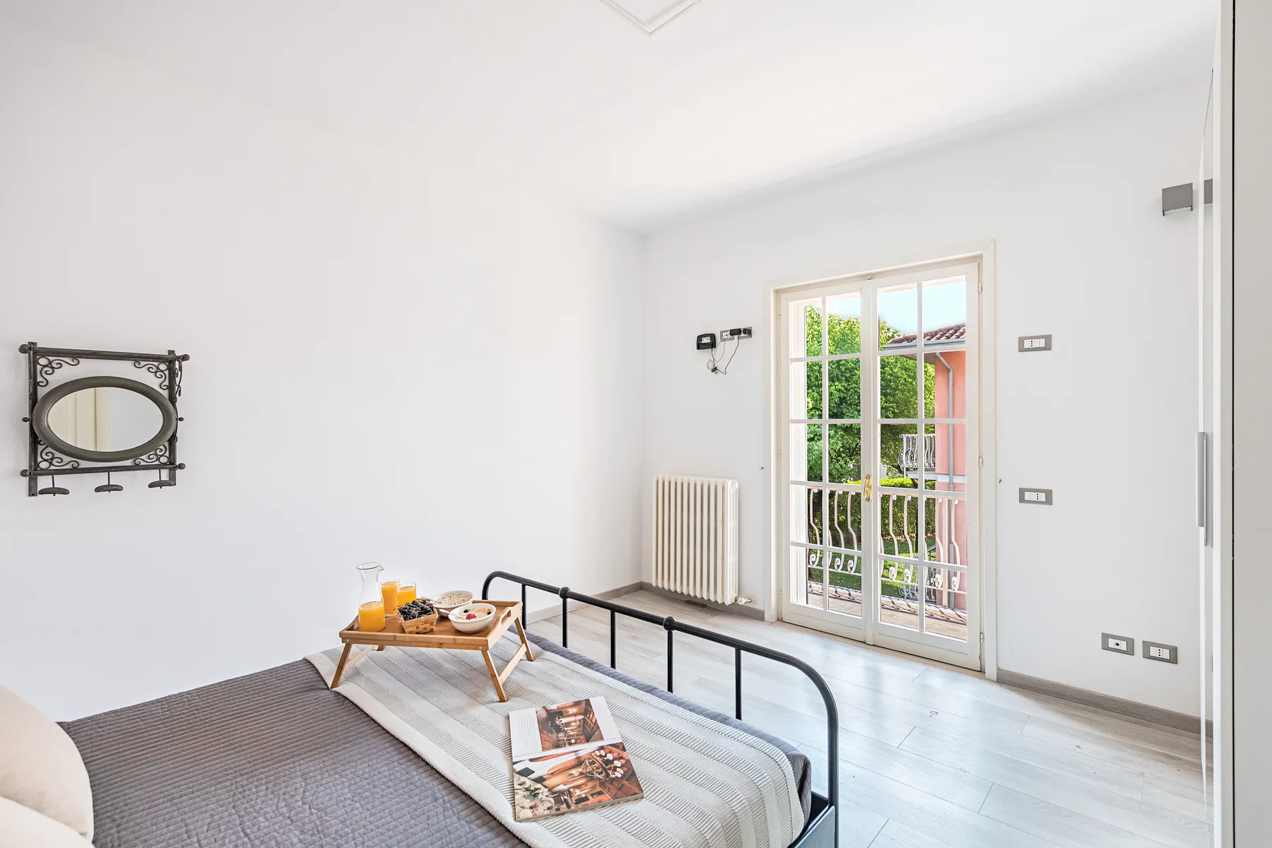 A bright bedroom with a bed and a glass door opening onto a balcony.