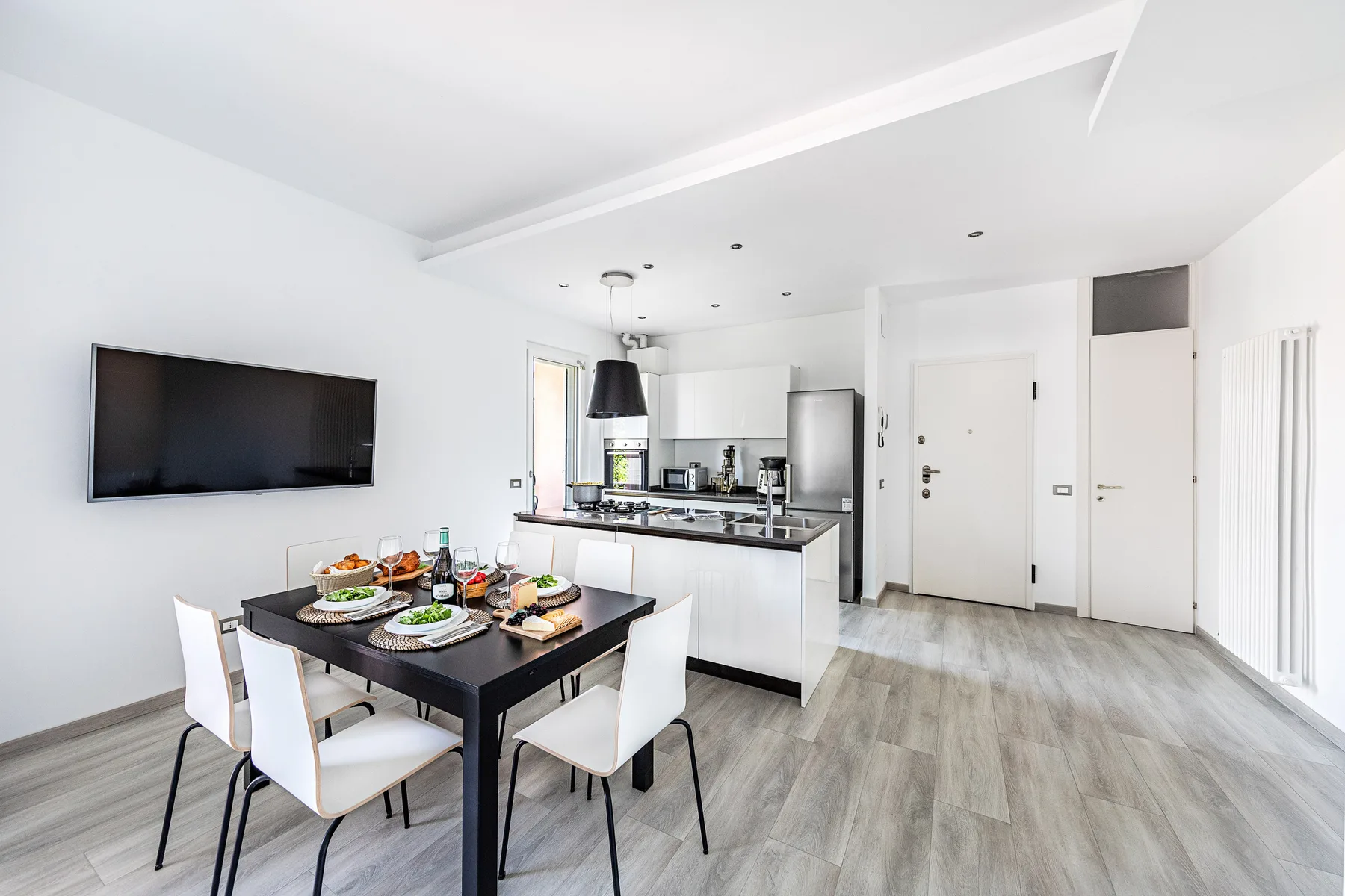 A bright open-plan kitchen and dining area with a table and wall-mounted television.