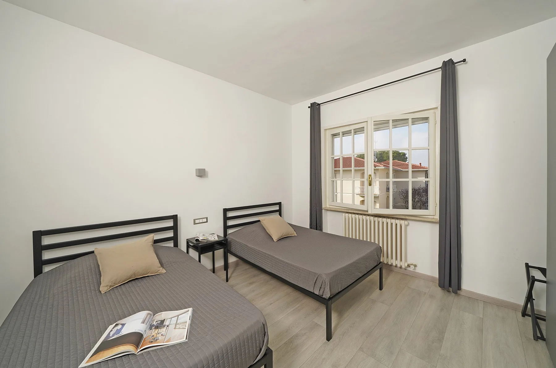 A bedroom with two beds, a window, and a radiator.